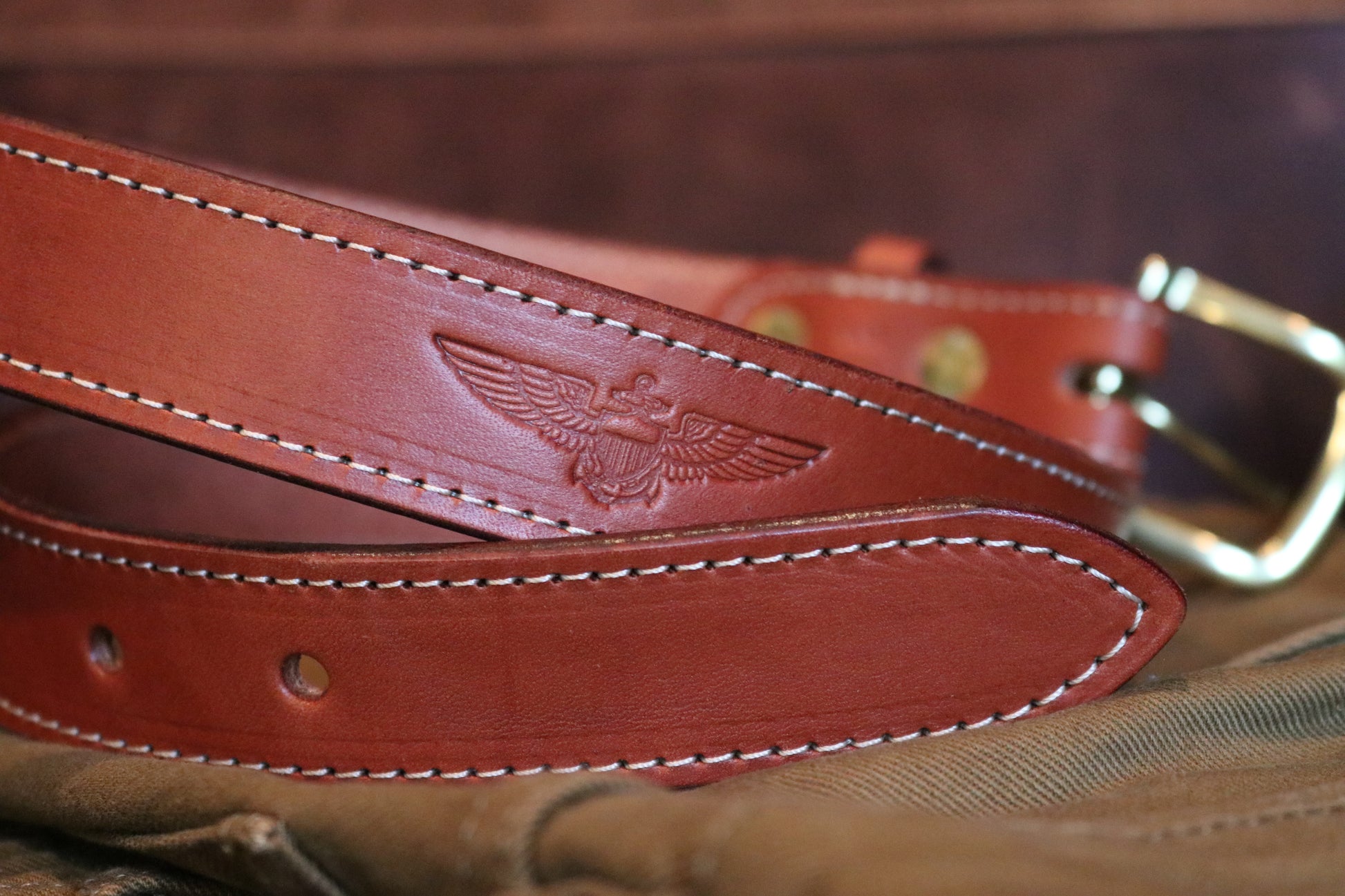 Handcrafted full-grain leather brown belt featuring a debossed Naval Aviator wing insignia. Handcrafted in Matthews, NC.